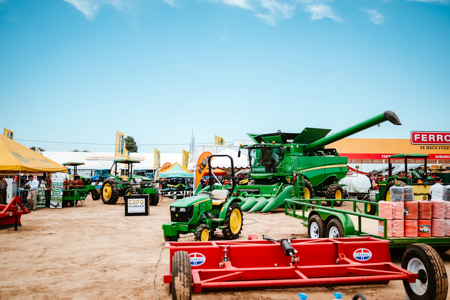 Green tractors and farm equipment displayed at an outdoor agricultural fair.